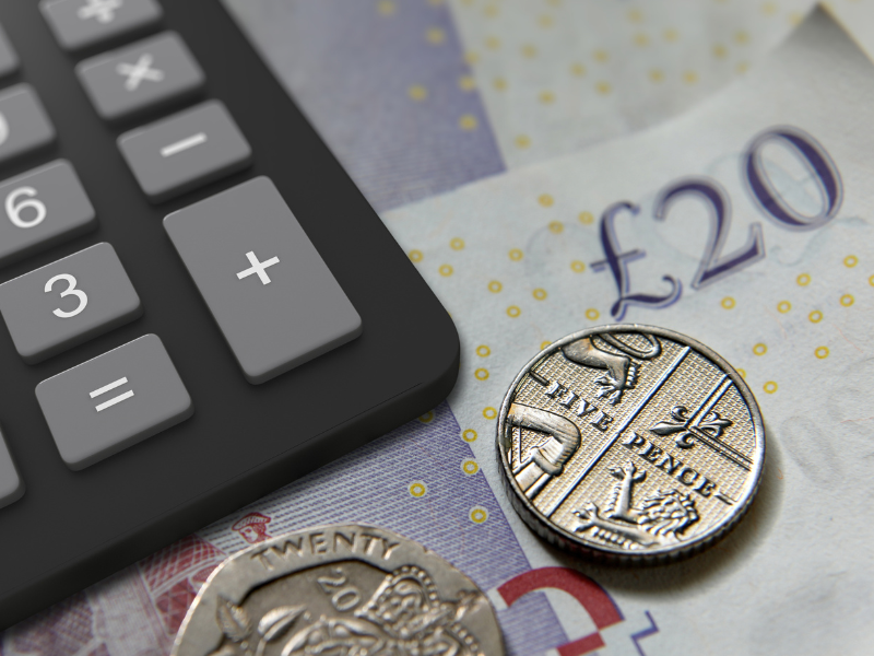 Black calculator with 5 pence piece and £20 notes